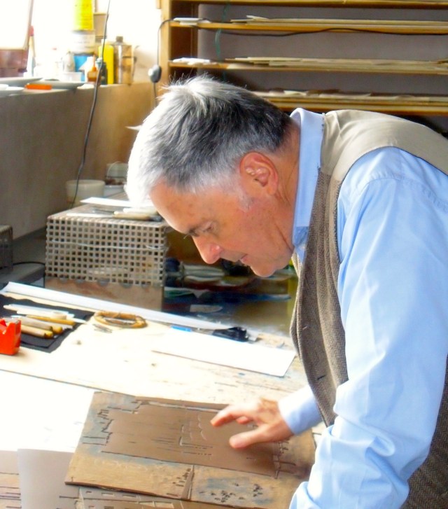 Der Künstler beugt sich in seinem Atelier über eine schon geschnittene Linolplatte